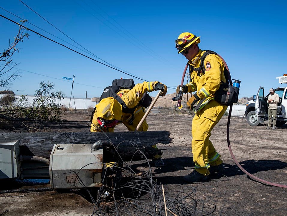 Feuerwehrleute untersuchen einen bei einem Buschfeuer umgestürzten Strommasten bei Santa Clarita in Kalifronien. (Bild: KEYSTONE/AP FR 171731/CHRISTIAN MONTERROSA)
