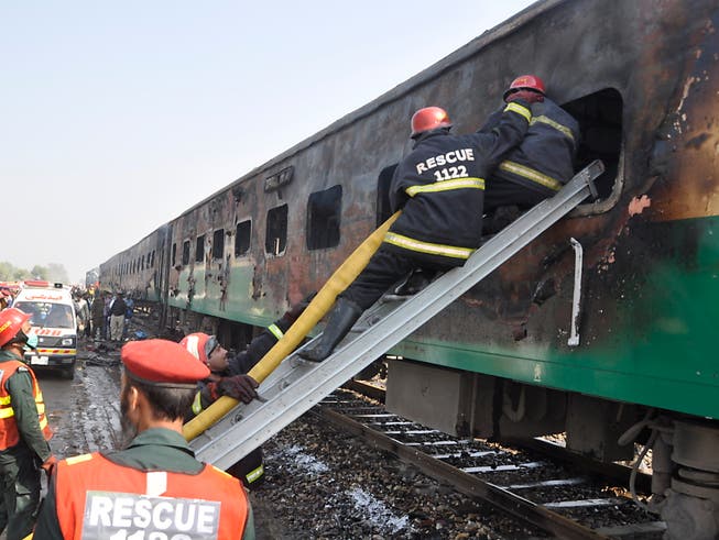 Rettungskräfte suchen nach Überlebenden des Brandes im Zug. (Bild: KEYSTONE/AP/SIDDIQUE BALUCH)