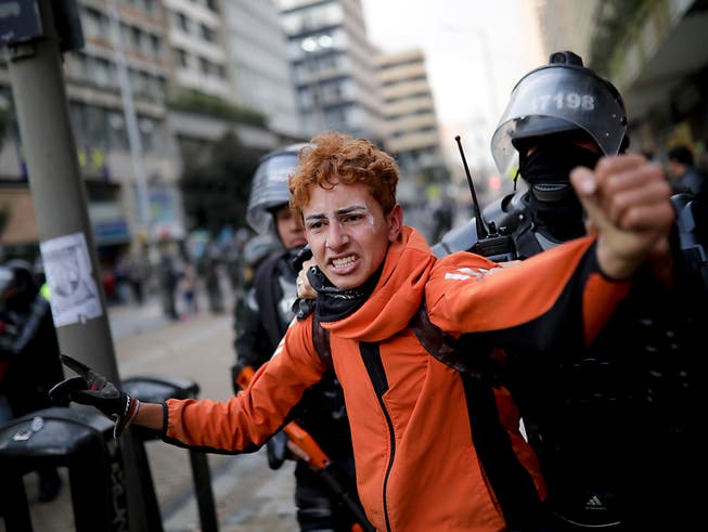 Kolumbianische Polizisten nehmen in der Hauptstadt Bogotá einen Anti-Regierungsdemonstranten fest. (Bild: KEYSTONE/AP/IVAN VALENCIA)