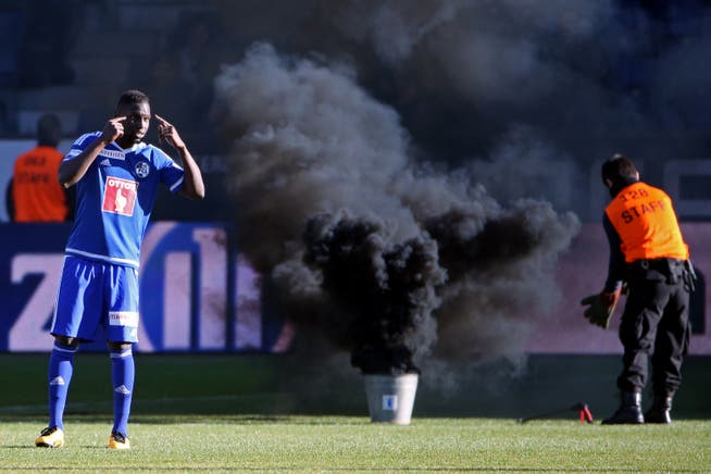 Ein Steward versucht, den Rauchkörper vom Spielfeld zu entfernen. Links im Bild: FCL-Spieler Sally Sarr. (Bild: Philipp Schmidli, Luzern, 21. Februar 2016)