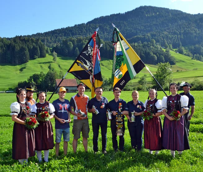 Die Festsieger des Obertoggenburger Feldschiessens 2019 in Nesslau, flankiert von den Fahnen und den Ehrendamen.