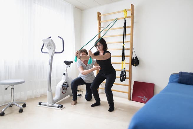 Eine Physiotherapeutin korrigiert die Übung einer Patientin. 