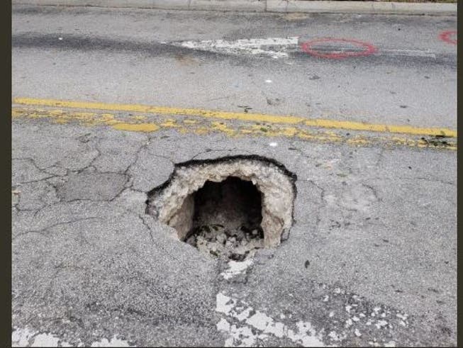 Auffälliges Loch mitten in der Strasse: Dieses führte zu einem Tunnel, der zu einer Bankfiliale in der rund 30 Kilometer nördlich von Miami gelegenen Stadt Pembroke Pines gegraben worden war. (Bild: Twitter / FBI Miami)