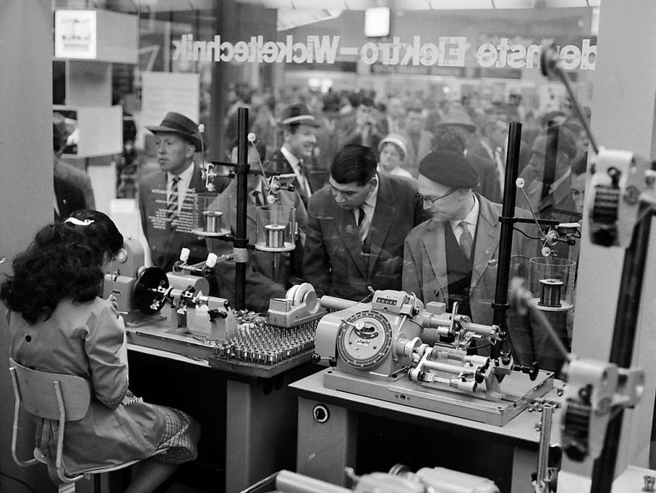 Besucher und eine Arbeiterin in der Maschinenhalle an der Mustermesse im Jahr 1960. (Bild: KEYSTONE/STR)