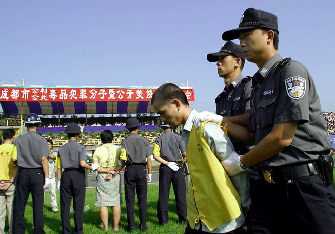 Chinesische Polizisten halten im Stadion in Shuangliu einen verurteilten Drogenhändler fest. (Bild: AFP)