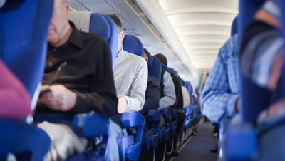 Aisle between the seats in the airplane cabin, shallow depth of focus. People out of focus.