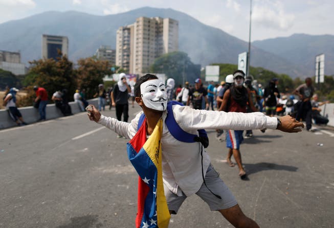 Ein regierungskritischer Demonstrant in Caracas wirft einen Stein in Richtung der Sicherheitskräfte. (Bild: Ariana Cubillos/AP, 1. Mai 2019)