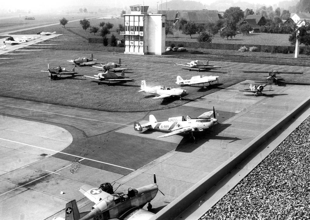 Blick auf den Militärflugplatz Emmen im Jahr 1962. Auf dem Bild zu sehen sind eine Pilatus P-2 und P-3, AT-16, C-36, Brücker Bü-133, Pilatus PC-6 «Porter »und im Hintergrund links eine DH-112 «Venom». (Bild: VBS)
