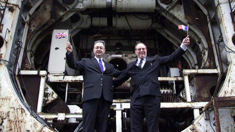 Die beiden Ingenieure Philippe Cozette (Franzose mit britischem Fähnlein) und Graham R. Fagg (Brite mit französischem Fähnlein) posieren zehn Jahre nach dem historischen Durchbruch vor der Eurotunnel-Bohrmaschine in Folkestone. (Bild: Hugo Philpott/Keystone, 1. Dezember 2000)
