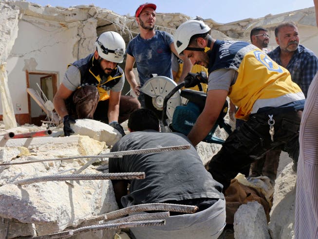 Rettungskräfte der Organisation Weisshelme suchen unter den Trümmern eines durch Luftangriffe zerstörten Gebäudes in Idlib nach Opfern. (Bild: KEYSTONE/AP Syrian Civil Defense White Helme)