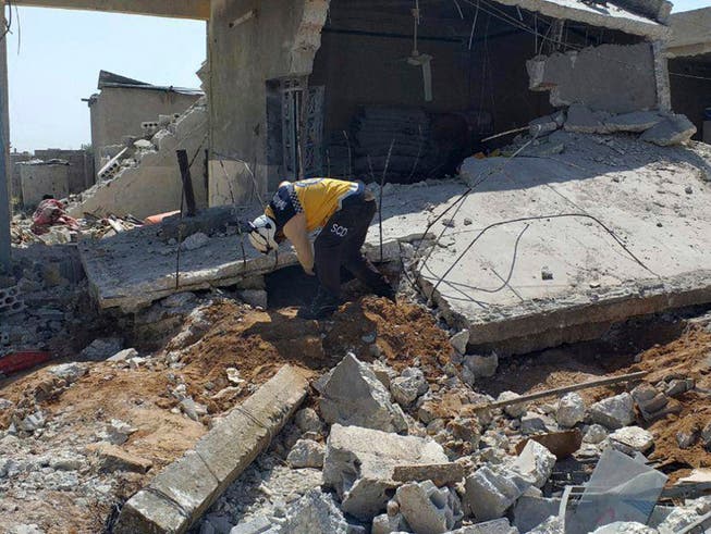 Ein Helfer der Organisation Weisshelme sucht unter den Trümmern eines Hauses nach möglichen Opfern. Das Haus im Dorf Ras al-Ain in der Provinz Idlib wurde durch Luftangriffe von Regierungstruppen zerstört. (Bild vom 7. Mai). (Bild: KEYSTONE/AP Syrian Civil Defense White Helmets)