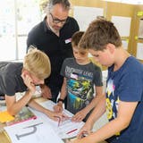 Architekt Felix Rutishauser rechnet mit drei jungen Teilnehmern Planmassstäbe um. (Bild: Christof Lampart)