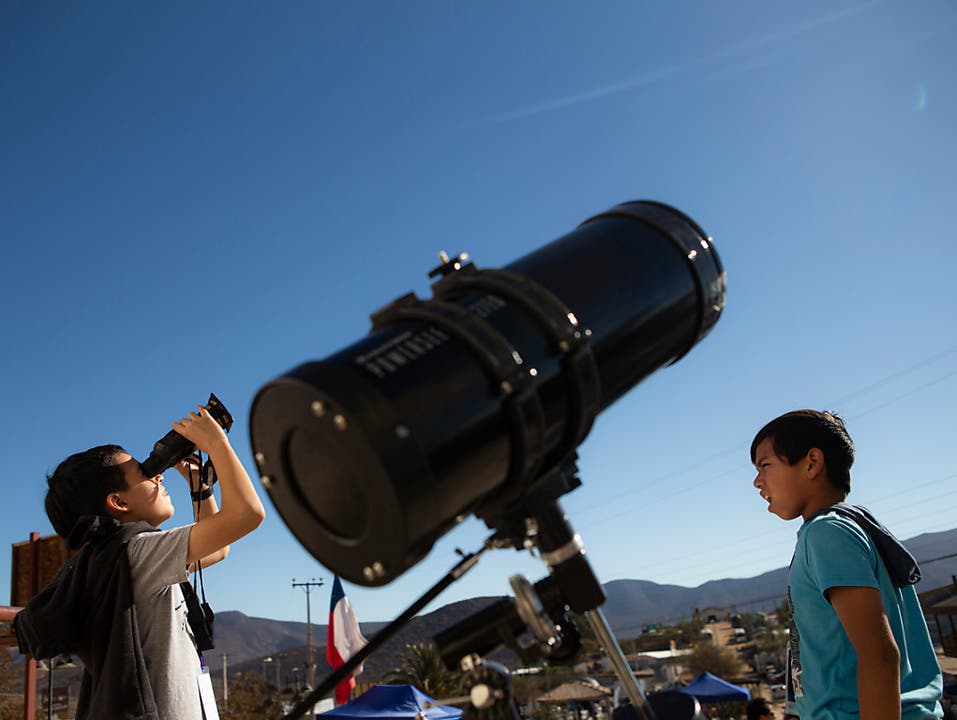 Auch Kinder in Chile testen Feldstecher, um die Sonnenfinsternis zu beobachten. (Bild: KEYSTONE/AP/ESTEBAN FELIX)