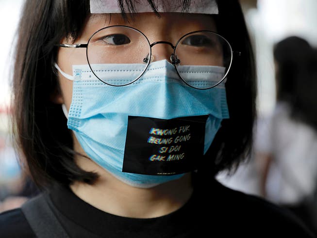 Eine Frau trägt während einer Anti-Regierungs-Demonstration in Hongkong eine Maske mit der Aufschrift «Fügt Öl hinzu, Leute aus Hongkong». (Bild: KEYSTONE/AP/VINCENT YU)