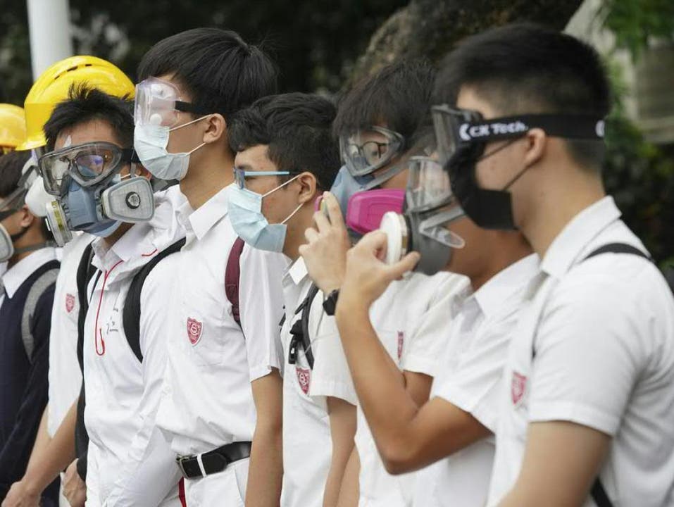 Studenten in Hongkong bilden Menschenketten aus Protest gegen die Regierung und die Zin Peking. Zum Schutz gegen Tränengas tragen sie Gasmasken und Skibrillen. (Bild: Keystone/AP)
