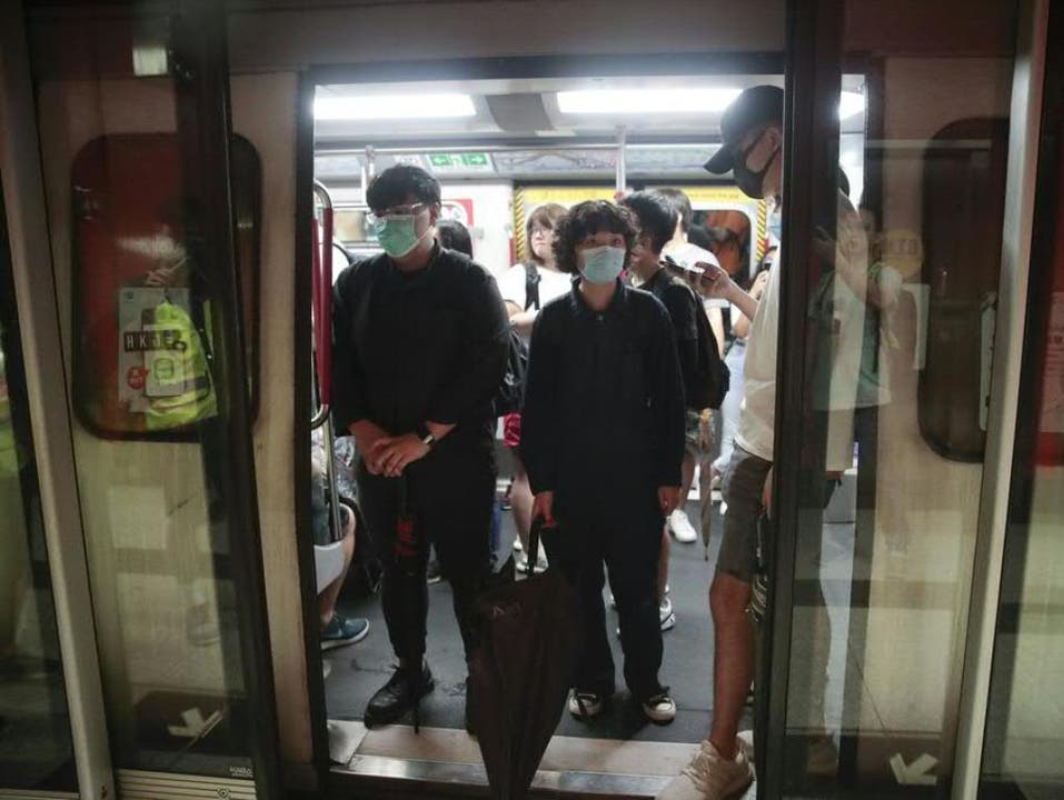 Schwarzgekleidete Demonstranten blockieren im morgendlichen Berufsverkehr in Hongkong die Türen zahlreicher U-Bahnen und halten sie so von der Weiterfahrt ab. (Bild: Keystone/AP/JAE C. HONG)