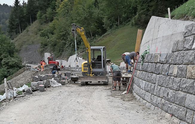 Equipen arbeiten an der Wiesenbergstrasse: Die erste Gruppe ist an der Natursteinverkleidung der Stützmauer und die zweite Gruppe erstellt die Planie für den folgenden Belagseinbau. (Bild: PD)