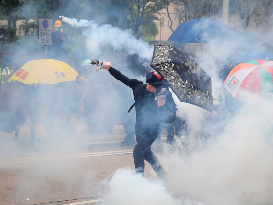 Protestierende Regierungsgegner in Hongkong werfen Tränengaspatronen zurück zu den Polizisten. (Bild: KEYSTONE/EPA/FAZRY ISMAIL)