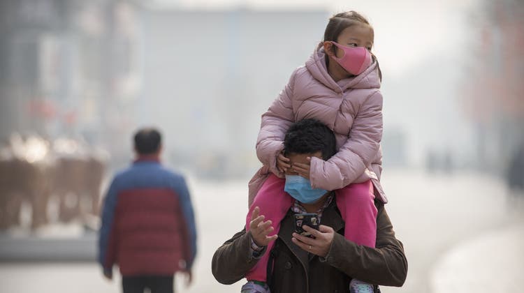 A girl wearing a face mask sits on a man's shoulders as they walk down a street in Beijing, Tuesday, Jan. 28, 2020. China's death toll from a new viral disease that is causing mounting global concern rose by 25 to at least 106 on Tuesday as the United States and other governments prepared to fly their citizens out of the locked-down city at center of the outbreak. (AP Photo/Mark Schiefelbein) (Mark Schiefelbein / AP)