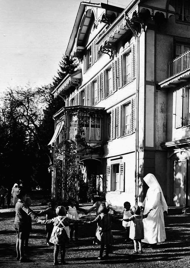 Spielende Kinder vor dem Kinderheim Theresia, aufgenommen um zirka 1930. Das 1881 gegründete Heim war das erste im Ägerital. Seit 1928 wurde es von den Schwestern des Klosters Heiligkreuz in Cham geführt.