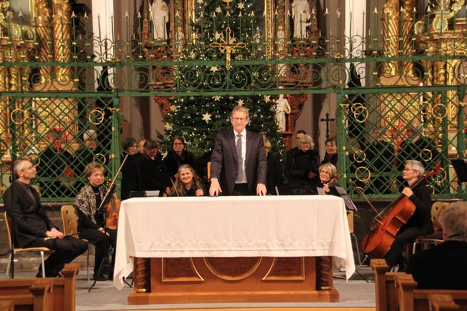 Marcel Schmid nimmt in der Klosterkirche Neu St. Johann den Applaus für die Uraufführung seines «Magnificat» entgegen. Der Chor singt hinter dem Chorgitter. 