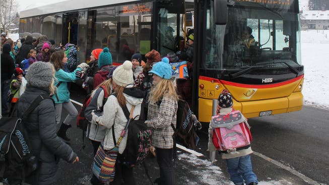 Schülerinnen und Schüler besteigen bei der Haltestelle Schulhaus Lüterkofen das Postauto.