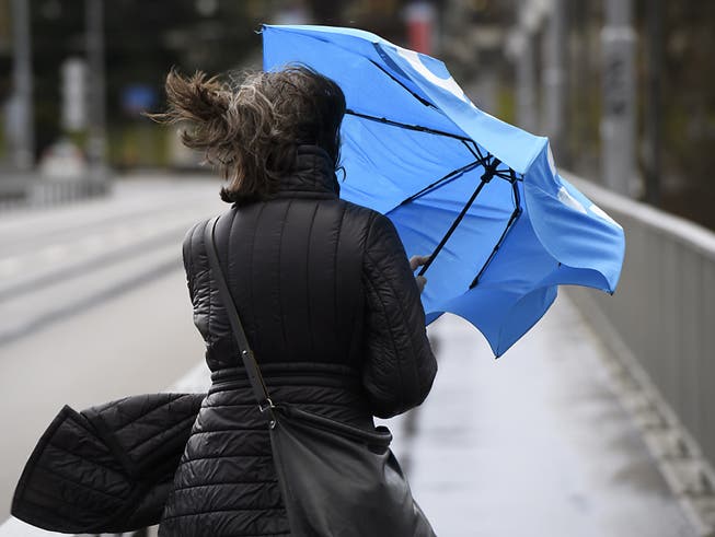 Stürmische Winde und viel Regen: Eine Frau kämpft mit den Tücken des Wetters.