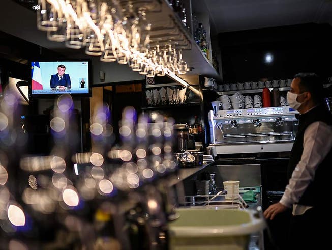 Emmanuel Macron, Präsident von Frankreich, ist auf einem Bildschirm eines Fernsehers in einem Café zu sehen. Foto: Christophe Simon/AFP/dpa