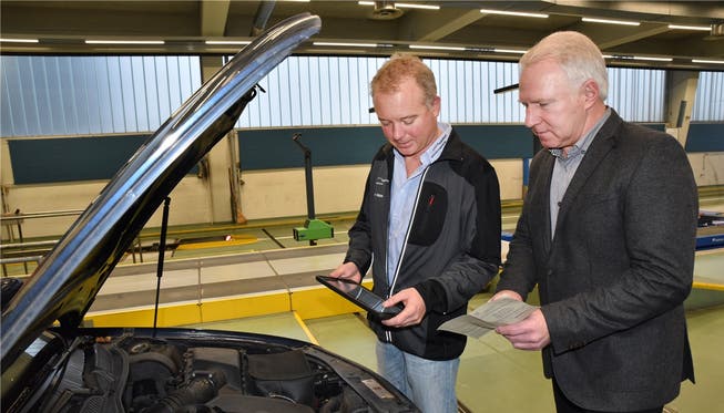 Verkehrsexperte Heinz Bichsel (l.) tippt Fahrzeugdaten neu in ein iPad ein. Rolf Bieber (r.), Leiter der Prüfstelle in Olten, hilft ihm dabei.