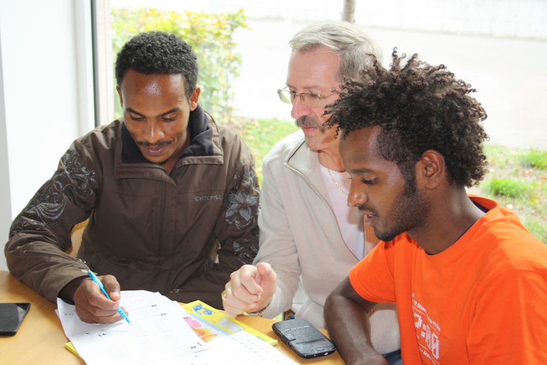 Alfred Messerli (Mitte) bringt zwei jungen Flüchtlingen Deutsch bei
