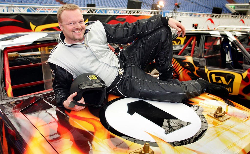 Raab posiert auf seinem Stock-Car auf der Pressekonferenz zur "TV-Total Stock-Car-Challenge" 2005.