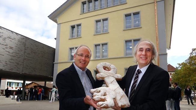 Schulleiter Urs Bögli und Baukommissionspräsident Gianni Asquini mit dem symbolischen Schlüssel vor dem renovierten Schulhaus 1.