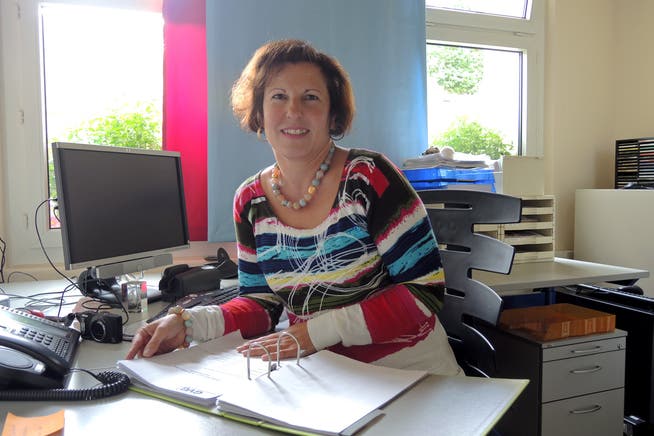 Claudia Bieri sitzt mit einem lachenden und weinenden Auge vor dem GREWA-Ordner in ihrem Büro.