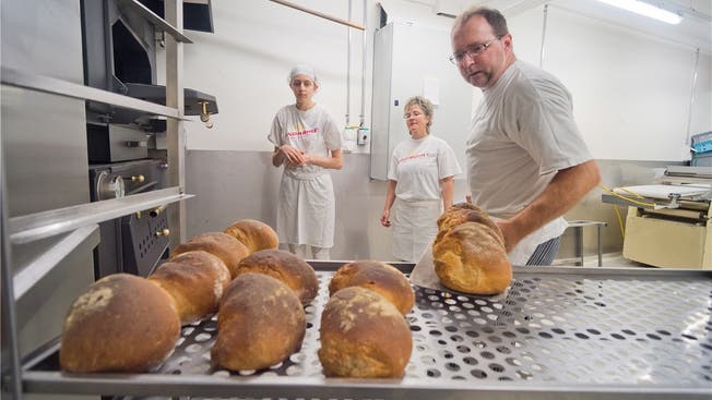 Bäckermeister Laurent Seiffert holt die Brote aus dem Holzofen, Noémi Lucas (links) und Monika Wernli helfen ihm dabei.