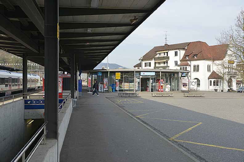 Das neue, kreisförmige Bahnhofgebäude mit Schalterhalle und Kiosk schiebt sich teilweise unter das Perrondach