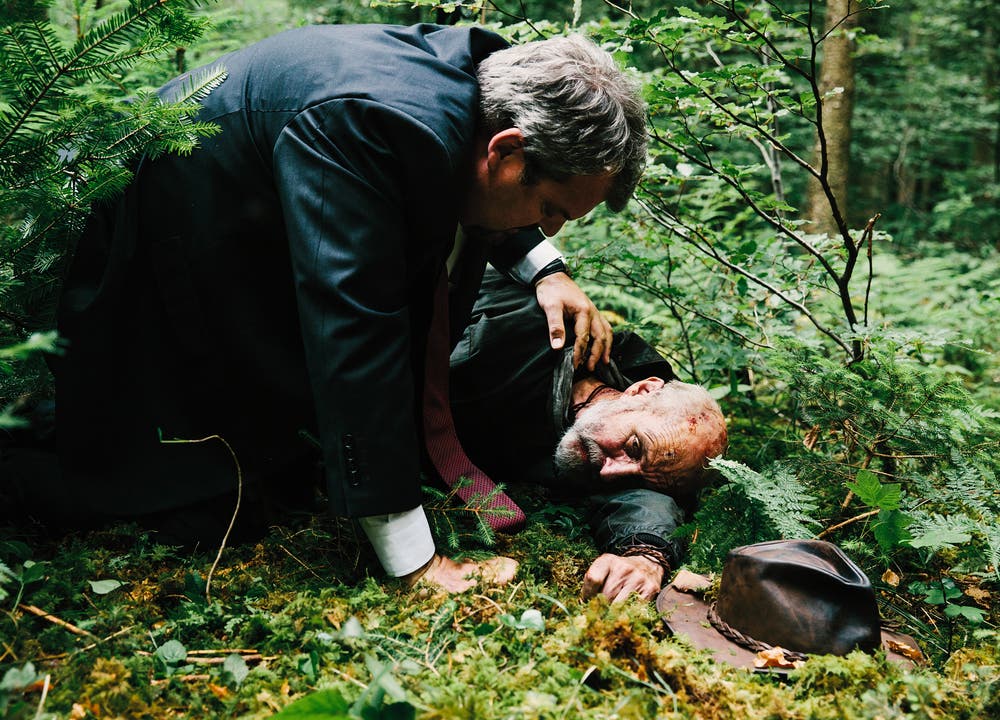 Lynchjustiz: Luc Conrad (Mike Müller) beugt sich über den «Schwarzkittel» (Peter Freiburghaus), den Dorfbewohner des Mordes verdächtigen und verprügelten. Folge 2: «Gefährliches Gelände»