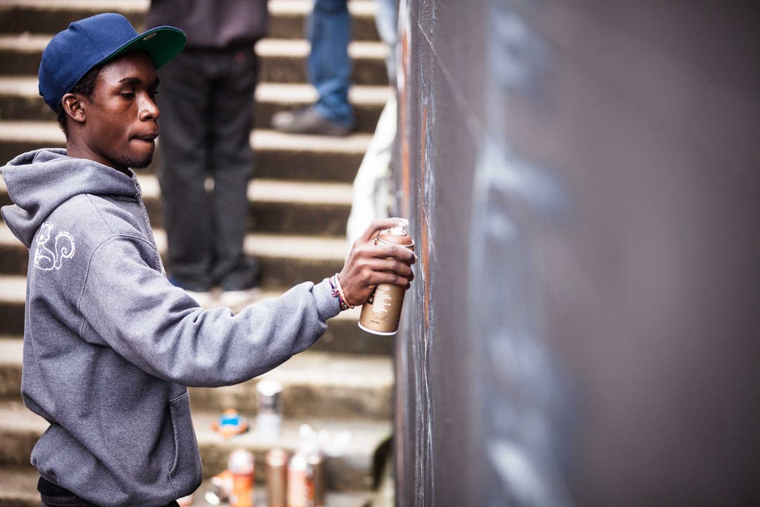 Ein Graffiti-Künstler aus Uganda gestaltet eine Wand bei der Halde Unterführung in Wohlen