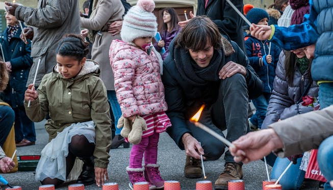 Singer und Songwriter Adrian Stern zündete mit den Kindern Kerzen vor der Katholischen Kirche an. Philippe Neidhart