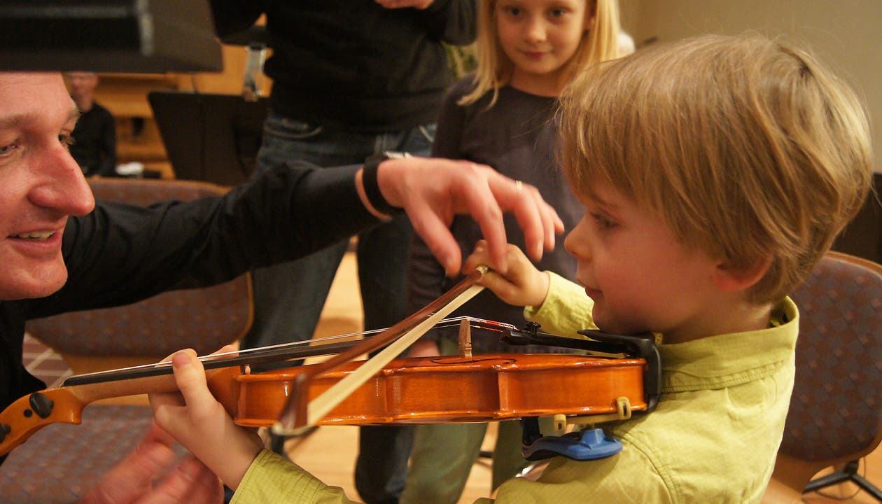 Silvan Meier erklärt einem Jungen, wie er den Geigenbogen richtig führen soll