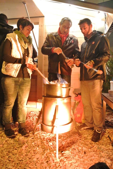 Nicole Lüthy von der Brennerei Humbel, Meisterkäser Rolf Beeler und Stadtrat Matthias Gotter giessen Kirsch übers Fondue, dann wird dieses flambiert.