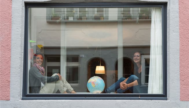 In der Milchgasse dreht sich die Welt: Die zwei Betreiberinnen Annette Kim (links) und Marisa Fricker sitzen im Schaufenster ihres Airbnb, in der Mitte eine Weltkugel. Auf dem Bild fehlen Charlotte den Hollander und Pueng That.