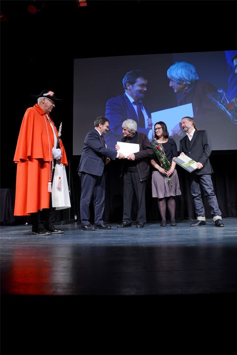 Landammann Roland Heim überreicht Paul Gugelmann den Kunstpreis. Beobachtet von Laudatorin Angela Kummer und Kuratoriumspräsident Christoph Rölli.
