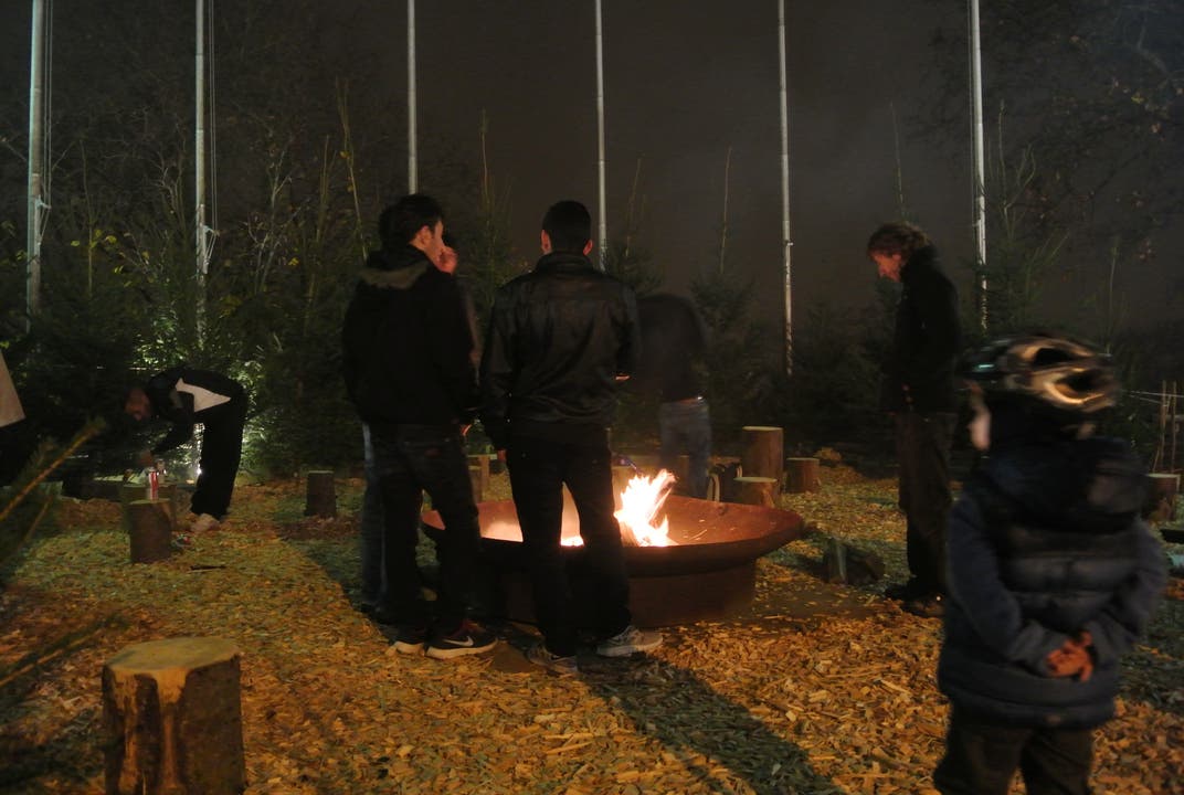 Während das Fondue aufgerührt wird, wärmen sich Passanten an der Feuerstelle auf
