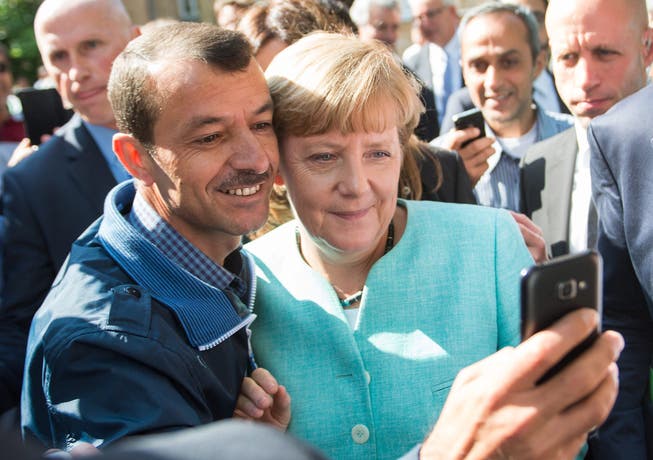 Selfie mit einem Flüchtling in der Asylunterkunft: Die deutsche Bundeskanzlerin Angela Merkel interessiert sich für das Schweizer Schnellverfahren.
