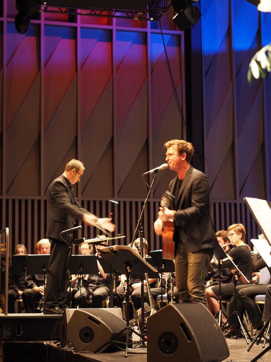 Zwei Männer vor grossem Orchester - Dirigent Christian Noth (links) und Gustav