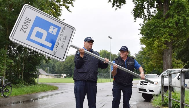 Heiner Hossli, Chef der Regionalpolizei Brugg (links), bringt mit seinem Kollegen Walter Huber die neue Signalisationstafel zum Standort am Brückengeländer