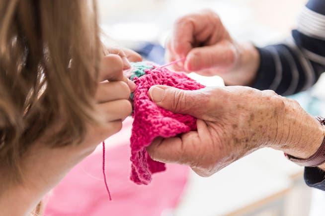 Eine Rentnerin hilft Pirmarschuelern freiwillig beim Textilunterricht.