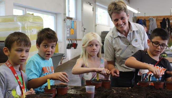 BBZ-Geschäftsleiterin Brigitte Vogel zeigt den Schülern wie Samen und Zwiebeln fachgerecht ins Pflanzentöpfli kommen.