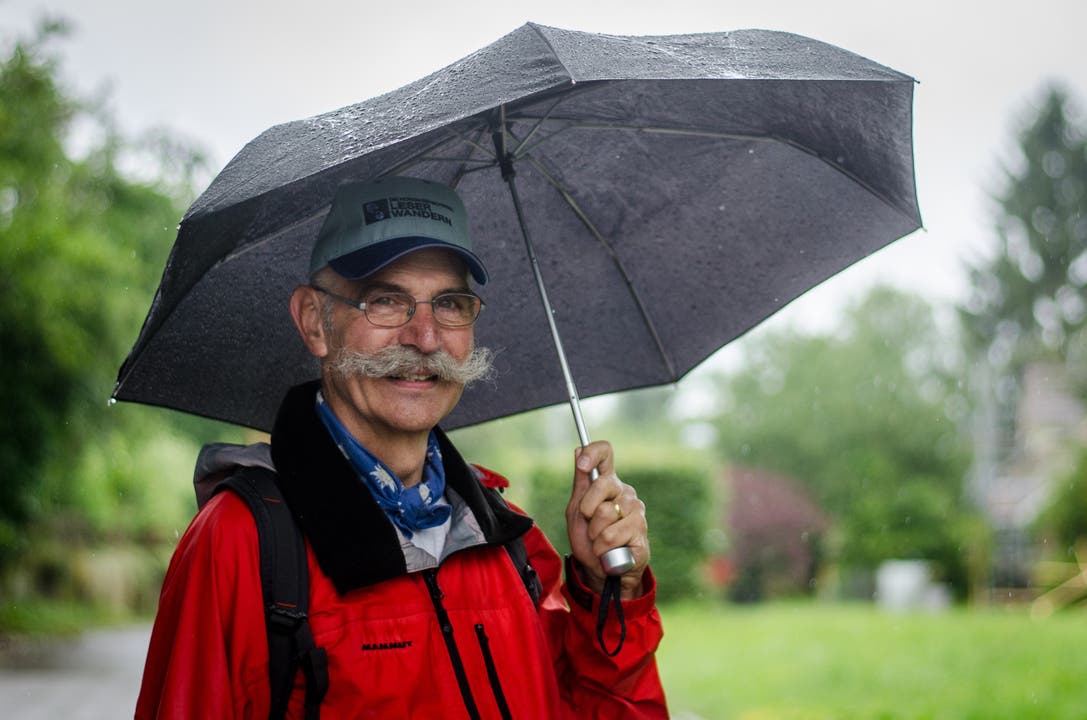 Leserwanderer Moritz Egloff mit Regenschirm und Leserwandern-Käppi sagt: "Das Wetter spielt mir keine Rolle"