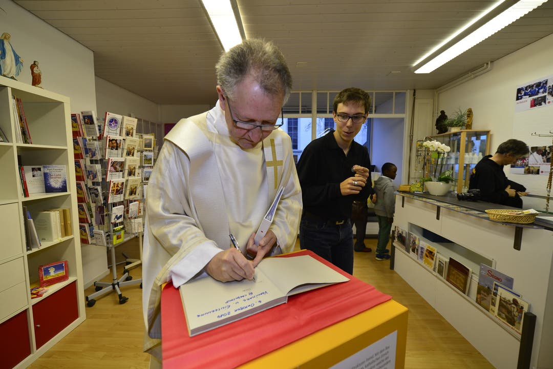 Pfarrer Mario Tosin trägt sich ins Gästebuch ein